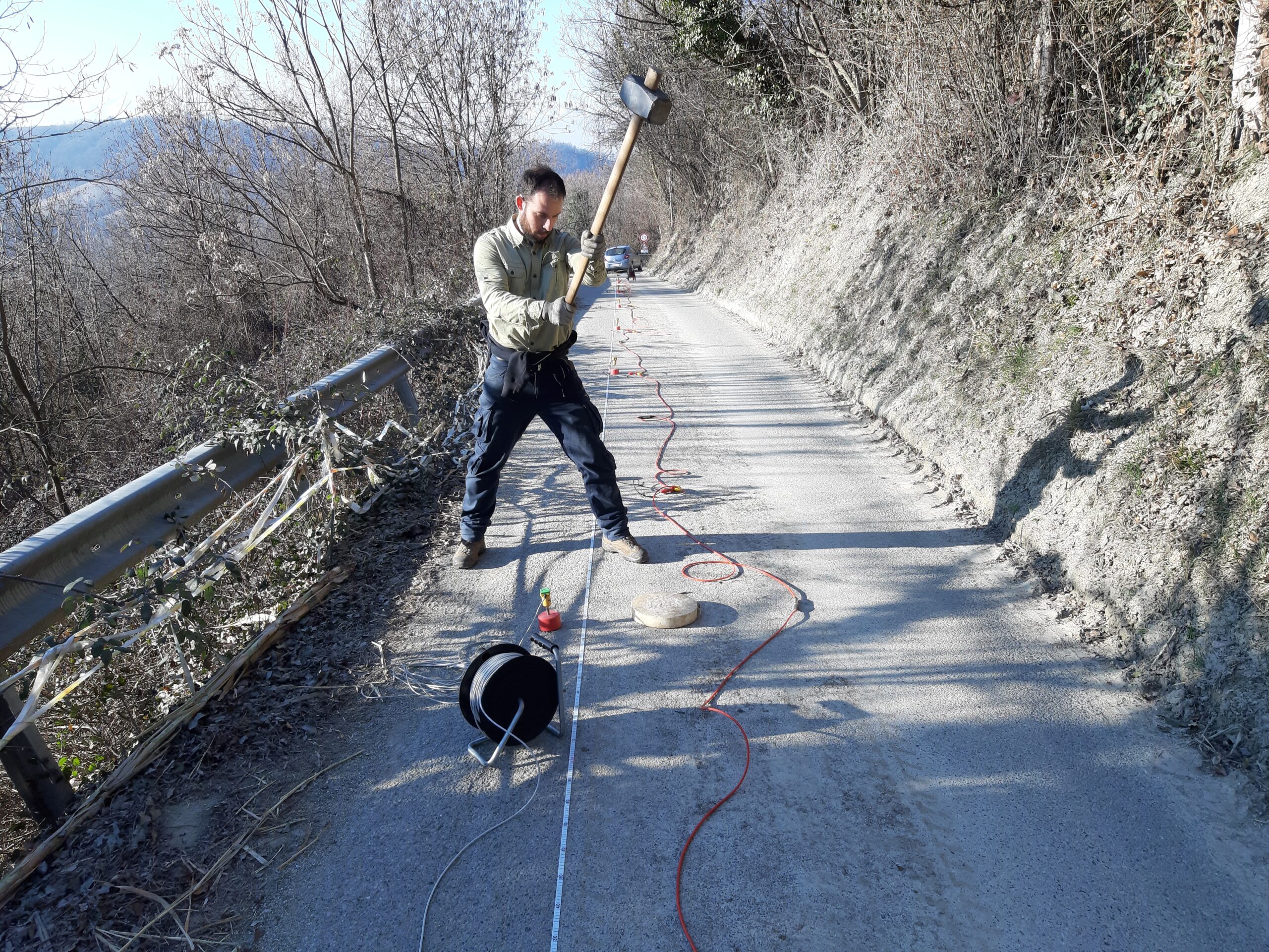 Geologo esegue indagine sismica su strada di montagna